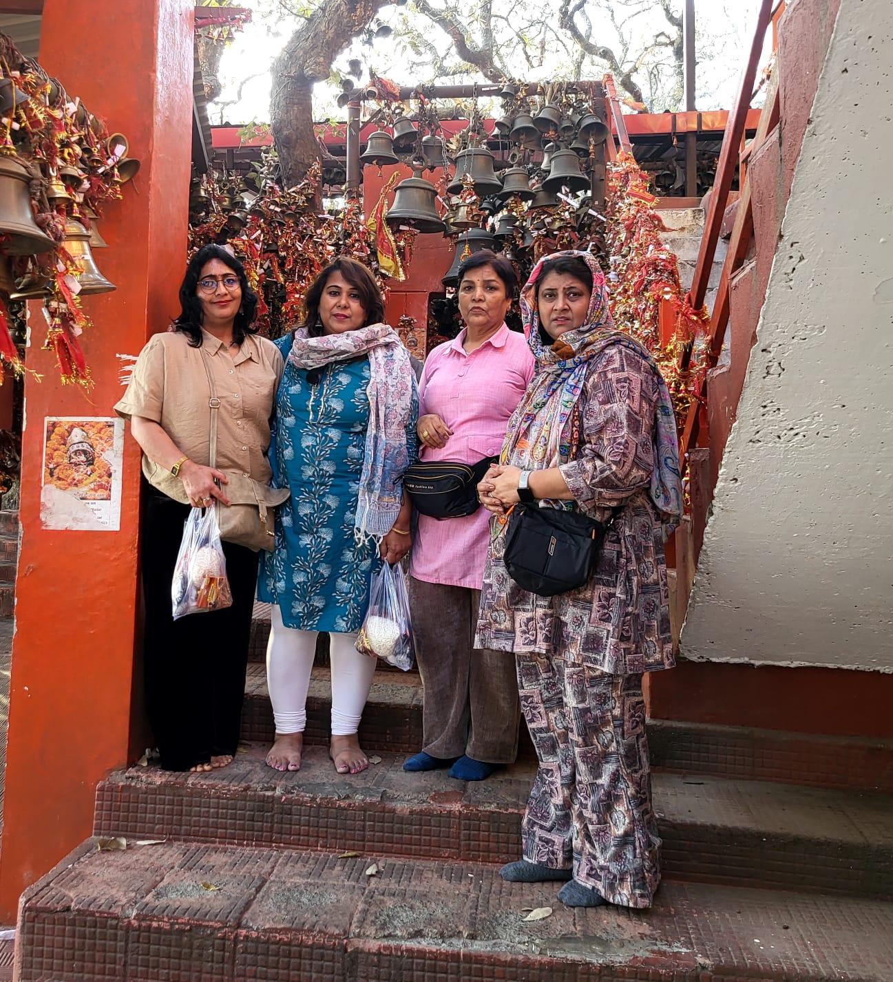 Women taking part in a quiet temple visit beneath rows of brass bells
