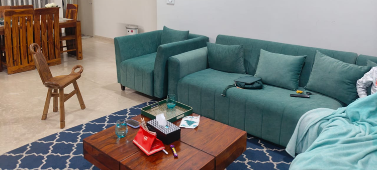 The Rai family’s existing living room with aquatic-blue seating, timber furniture and a patterned blue rug