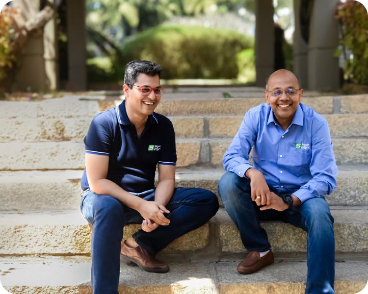 The two MoveInSync founders sitting on the steps outside the office