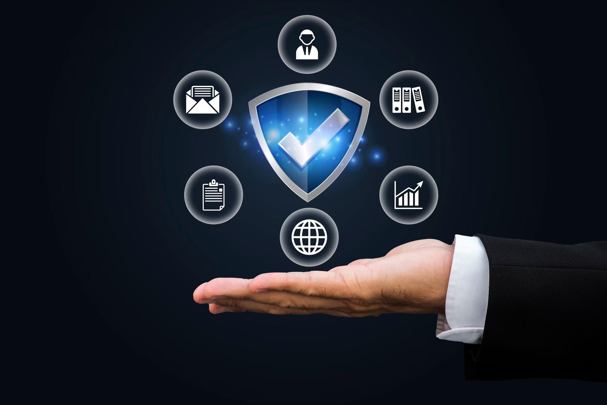 A security shield held above an open hand, ringed by data and compliance icons