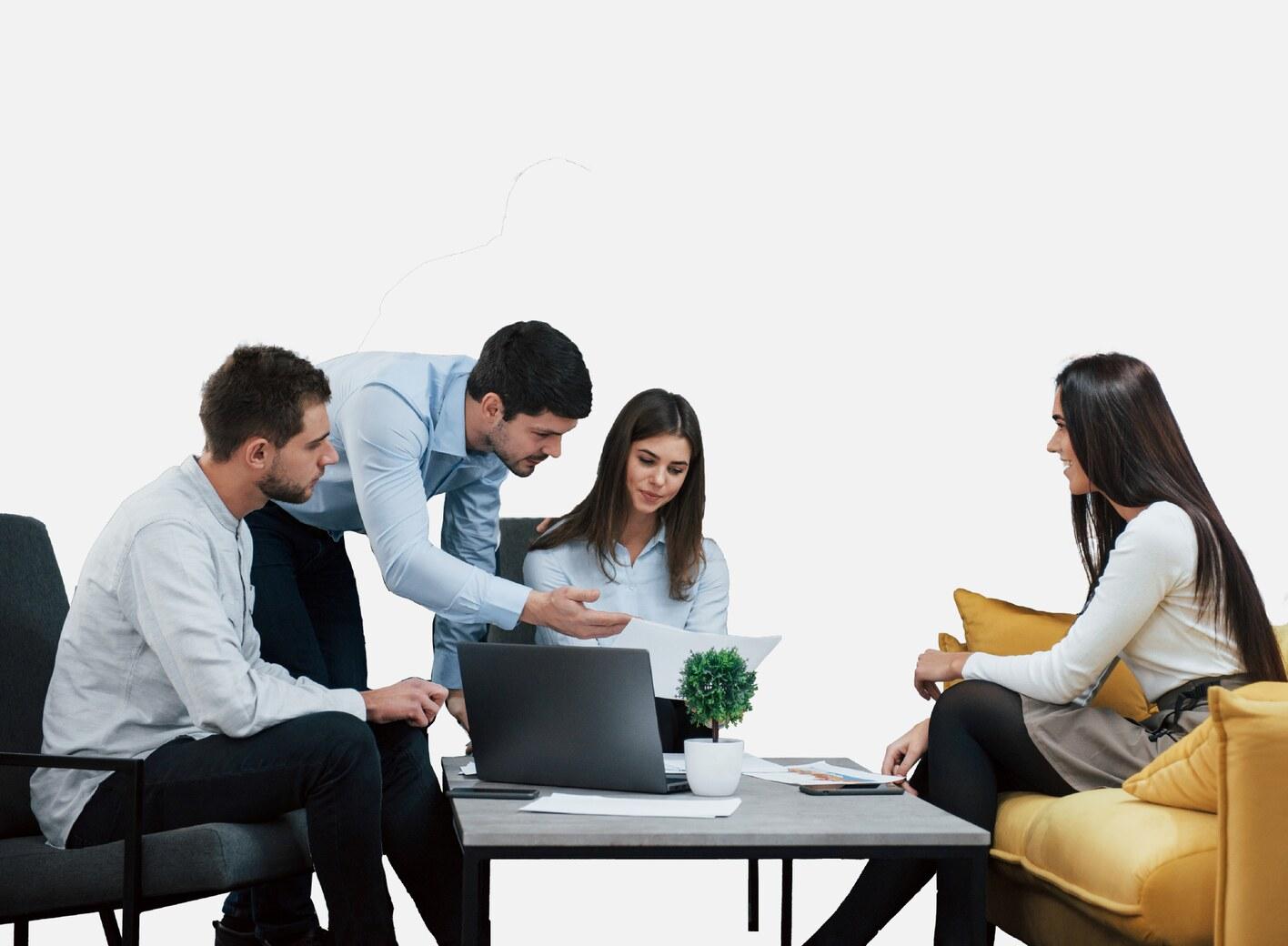 Four colleagues gathered around a laptop in an office lounge, talking through a printed document
