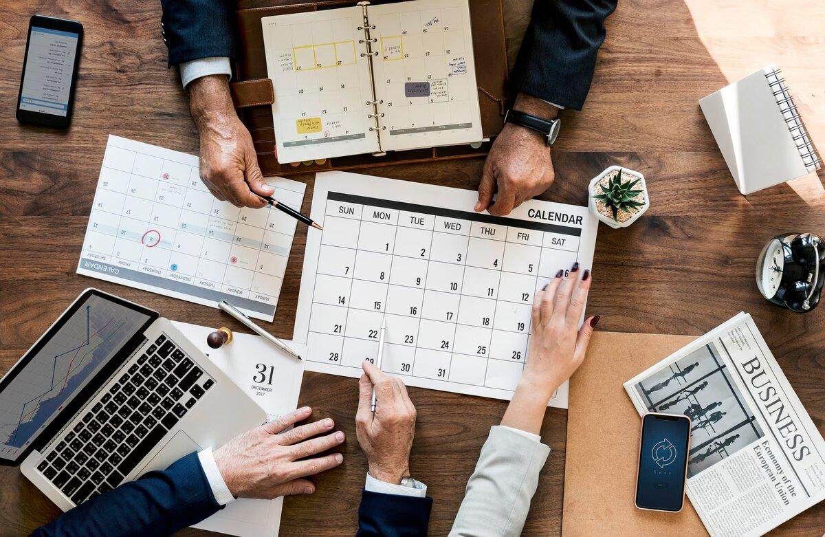 Colleagues planning the week across desk calendars and a laptop
