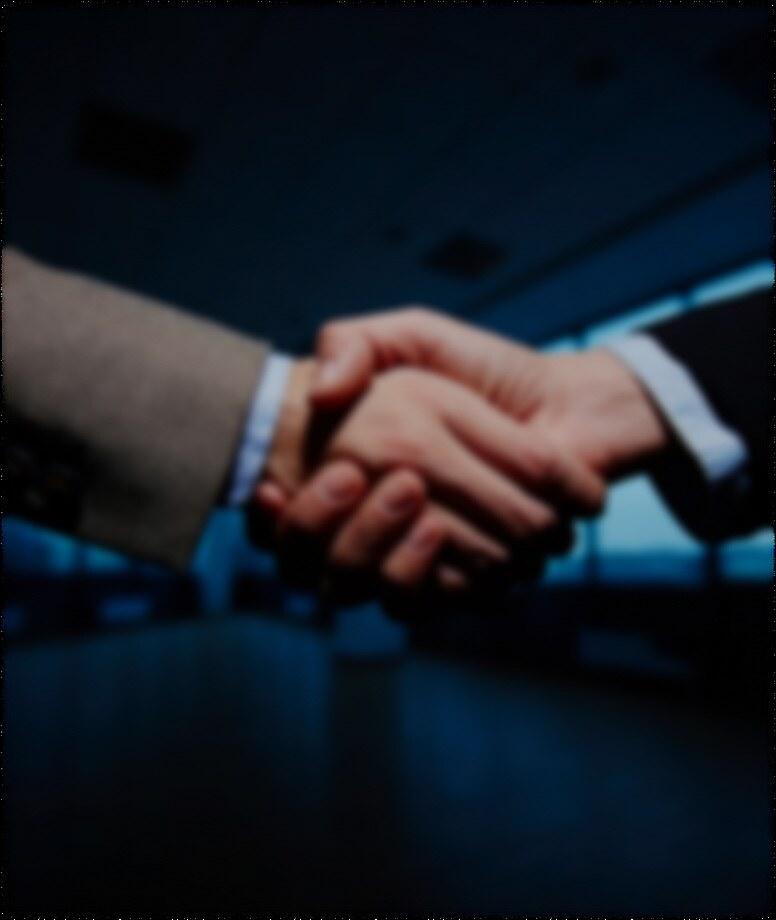 Two people shaking hands across an office desk