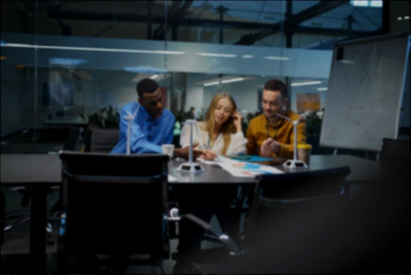 A team reviewing wind turbine models in a glass meeting room