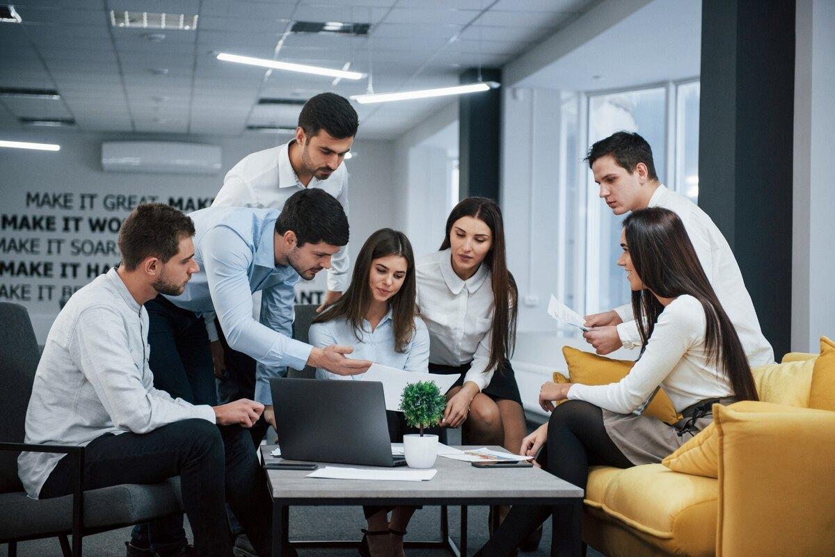 A team gathered around a laptop in an open office lounge
